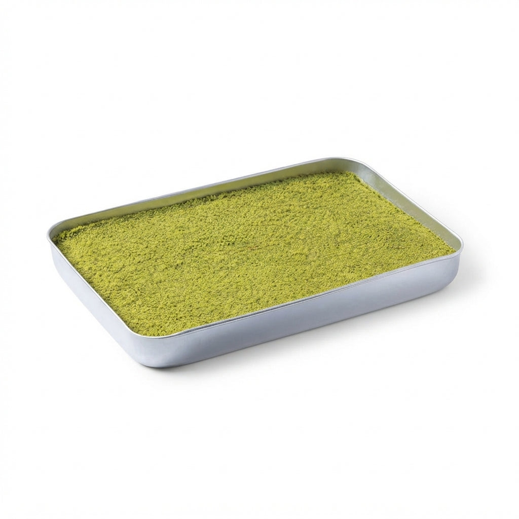 A rectangular silver metal tray filled with a fine, bright yellow-green pistachio powder, photographed on a clean white background.