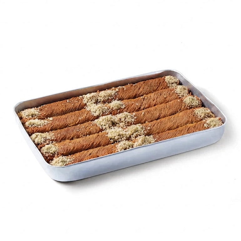 A rectangular metal baking pan filled with rolled cinnamon sticks or baklava, topped with chopped nuts, on a plain white background.