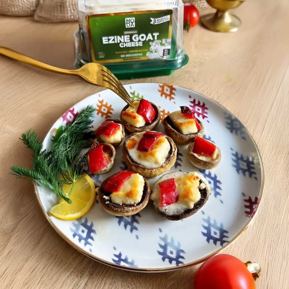 Packaged Ezine Goat Cheese in a vacuum-sealed container with a green lid, labeled with the brand MODA, product name, weight, and an illustration of goats on the front.